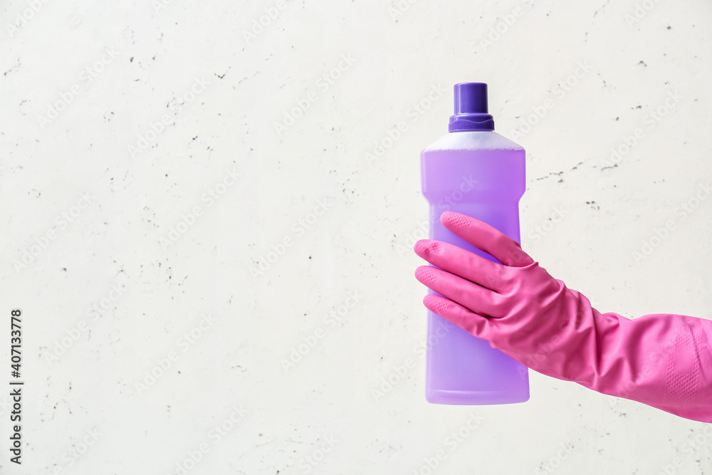 Hand in rubber glove with detergent on light background