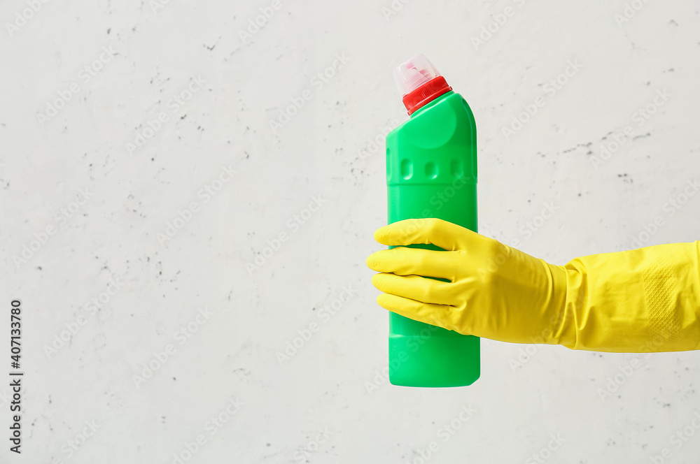 Hand in rubber glove with detergent on light background