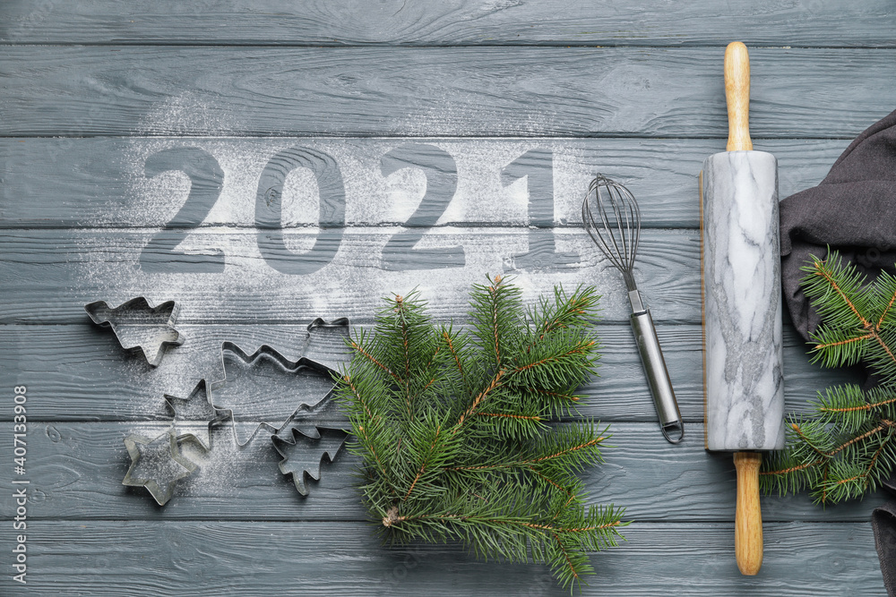 Cookie cutters, utensils and text 2021 on wooden background