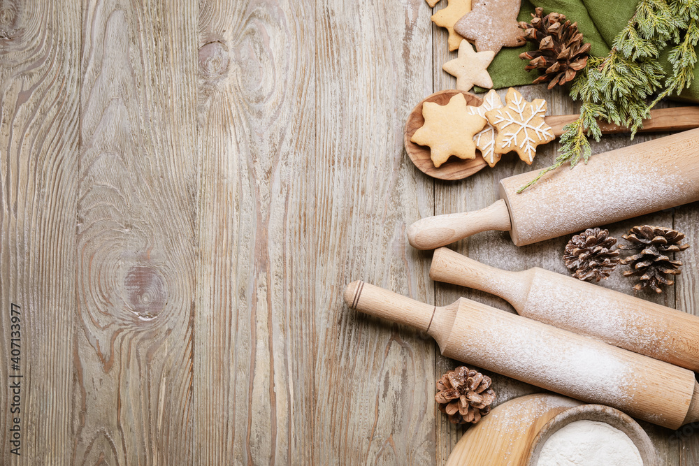 Christmas tree branches, tasty cookies and rolling pins on wooden background