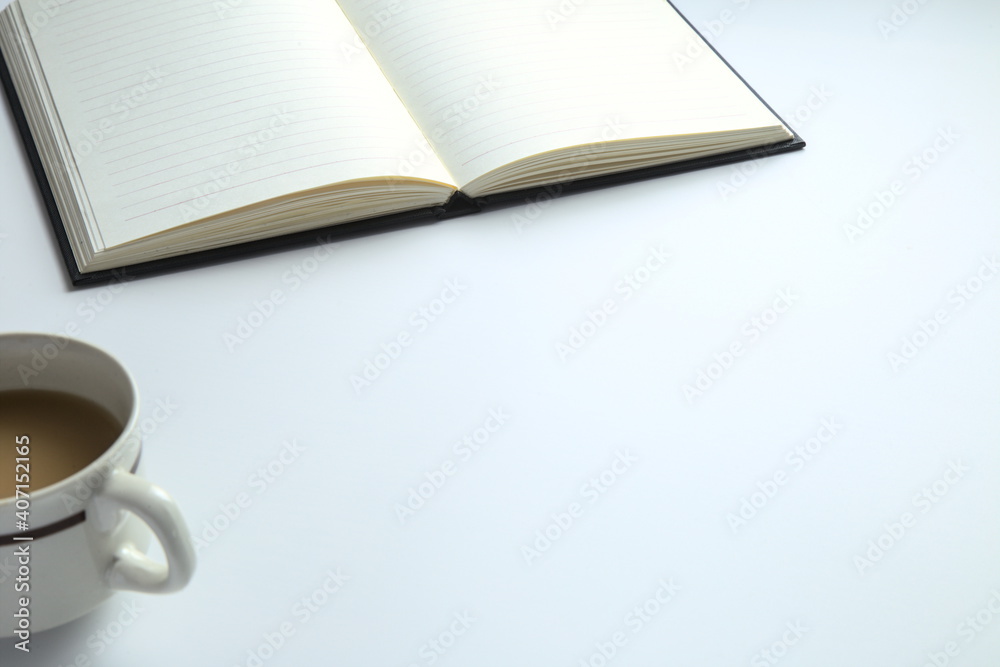 Open notebook and coffee on the desk, white background, copy space