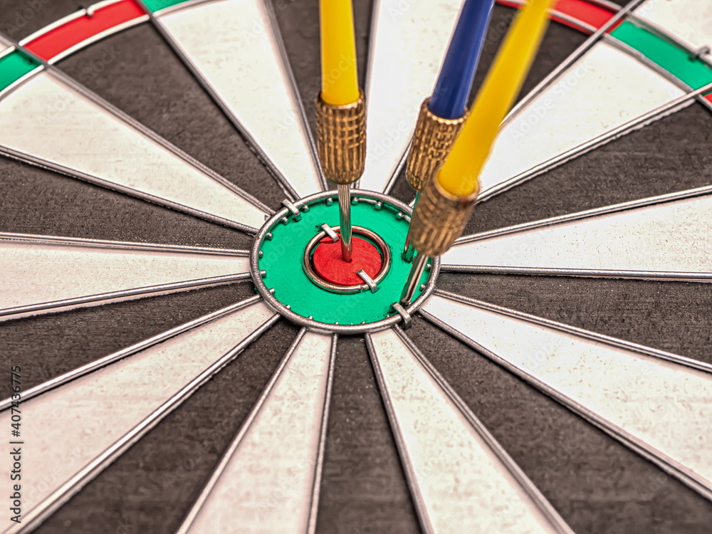 Side view of a dartboard with three darts in the bulls eye. Well-aimed dart throwing. Triple bulls