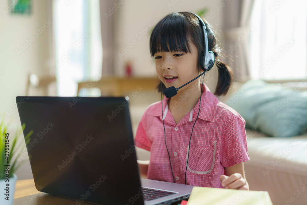 亚洲女学生与老师和同学在客厅的电脑上进行视频会议电子学习