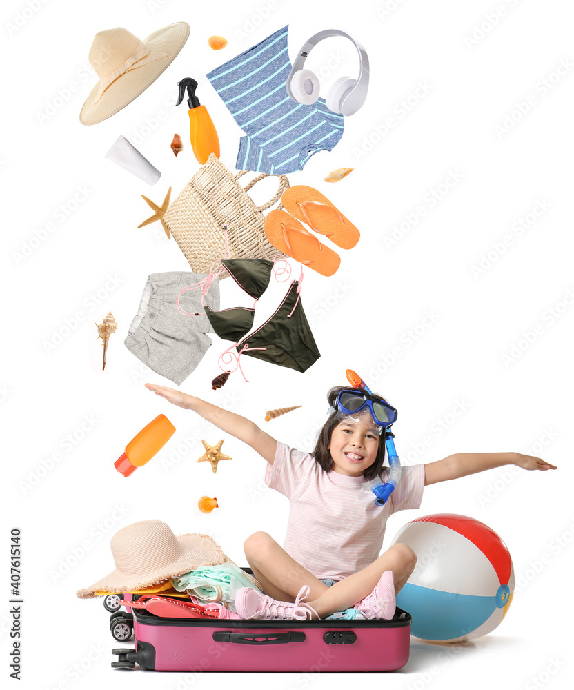 Happy girl with suitcase and falling belongings on white background