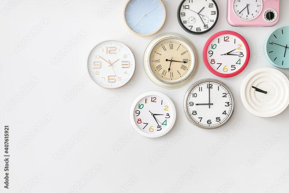 Different clocks hanging on light wall