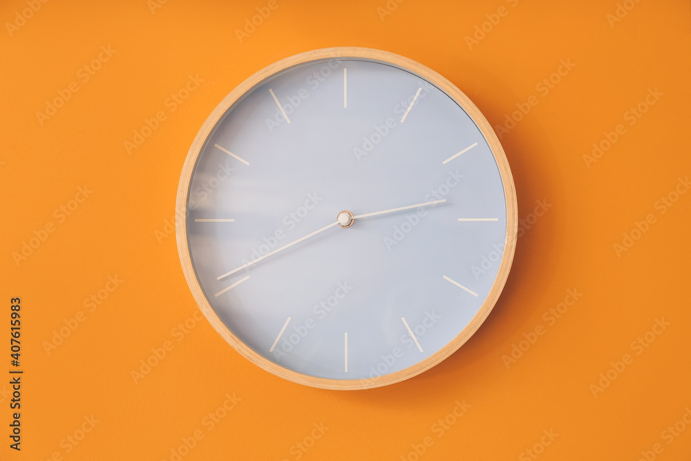 Modern clock hanging on color wall