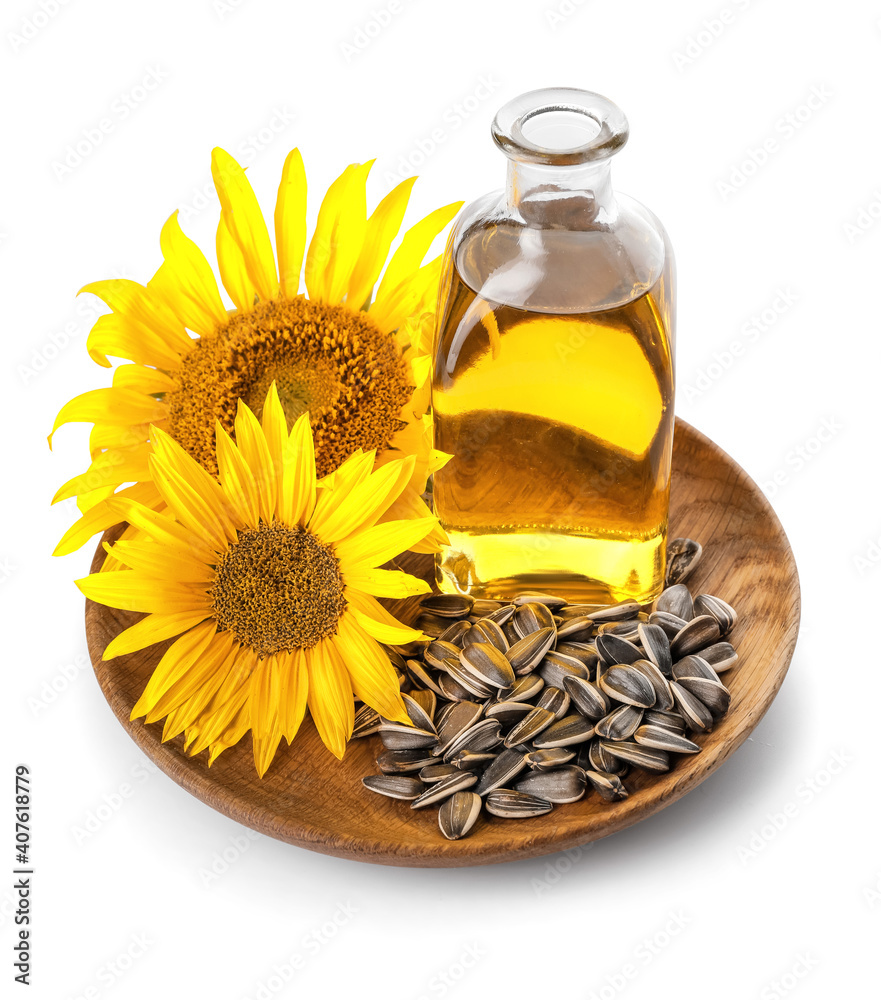 Bottle of oil, seeds and sunflowers in plate on white background