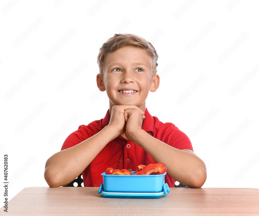 Schoolboy with lunchbox on desk against white background