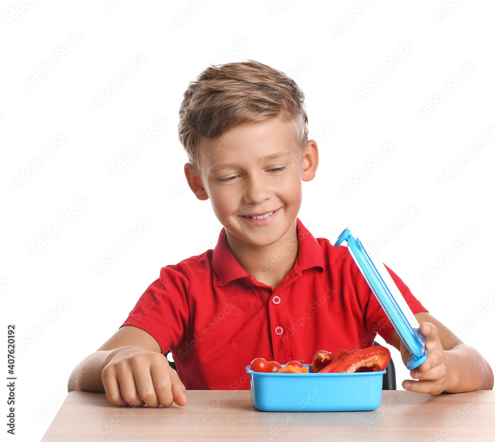 Schoolboy with lunchbox on desk against white background