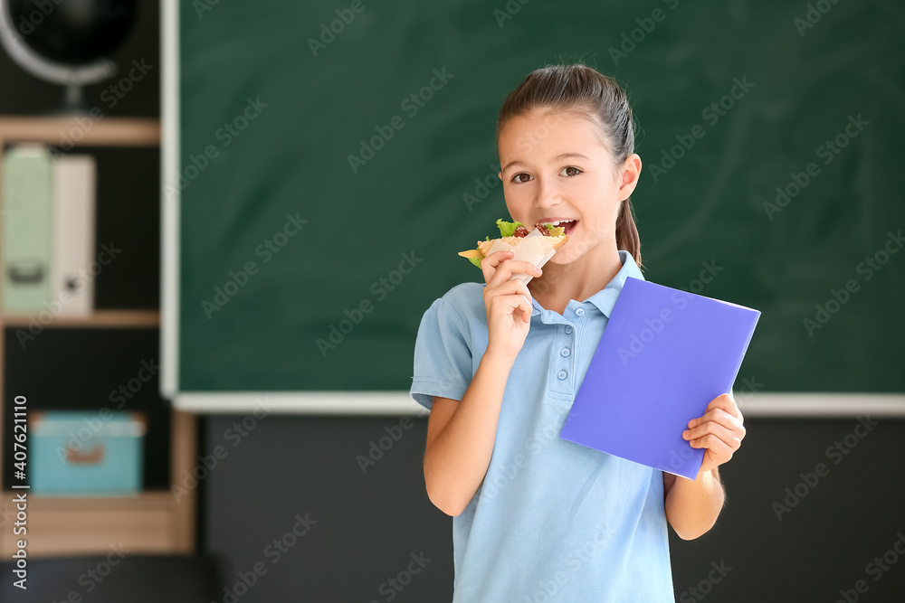 女学生在学校模糊背景下吃三明治