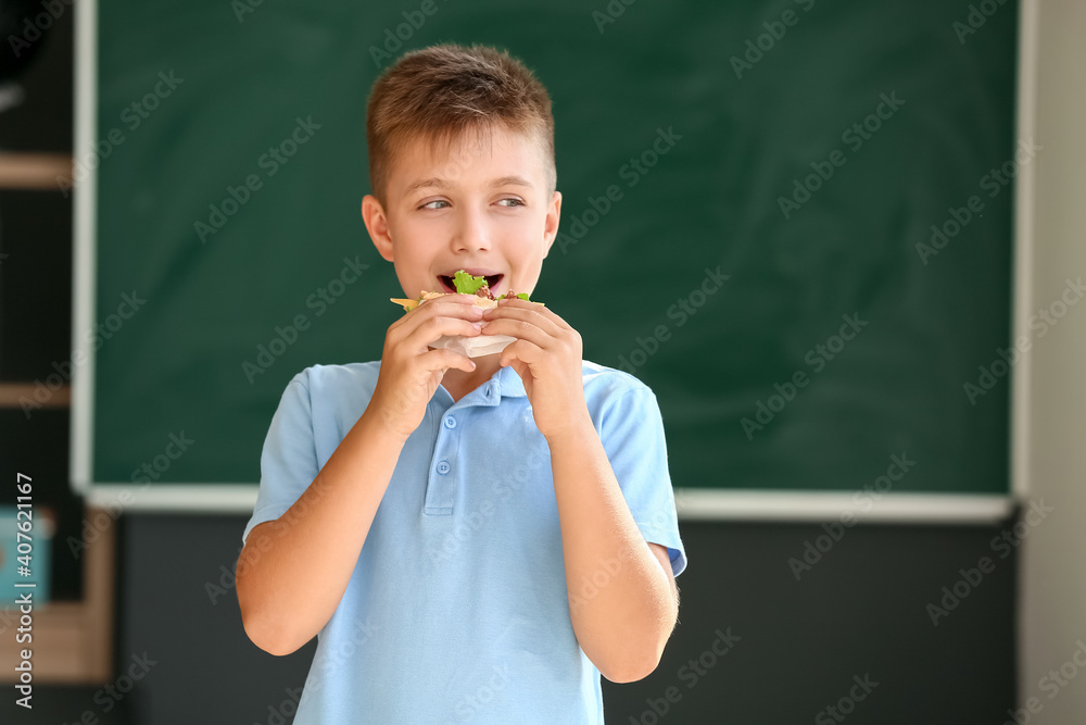 一名男生在学校模糊背景下吃三明治