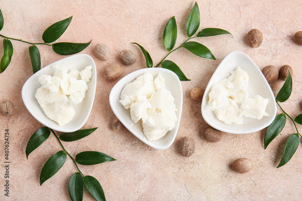 Bowls with shea butter on color background