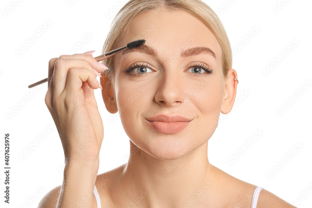 Young woman correcting her eyebrows on white background