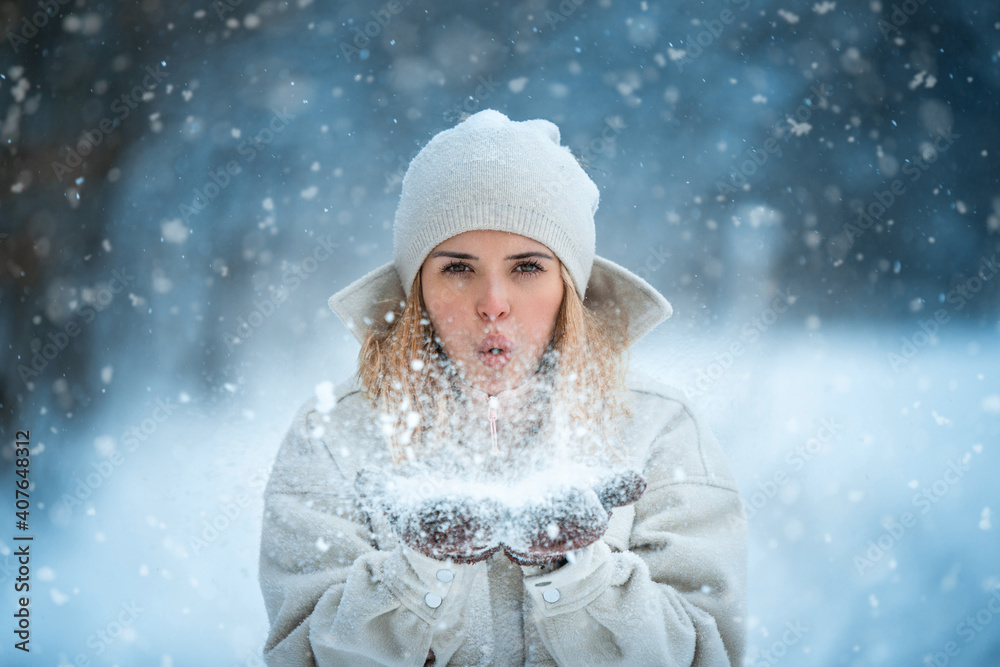 美丽的女人在雪地公园吹雪