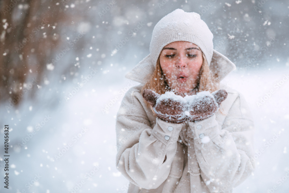 冬天的女人在公园里散步时吹雪