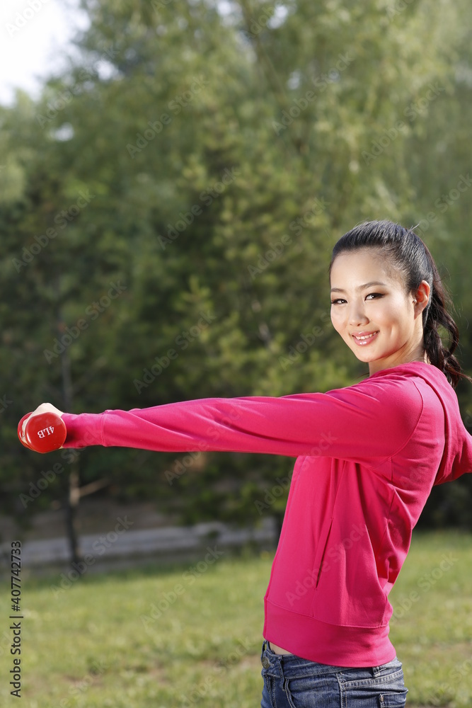 年轻女子在户外用哑铃锻炼