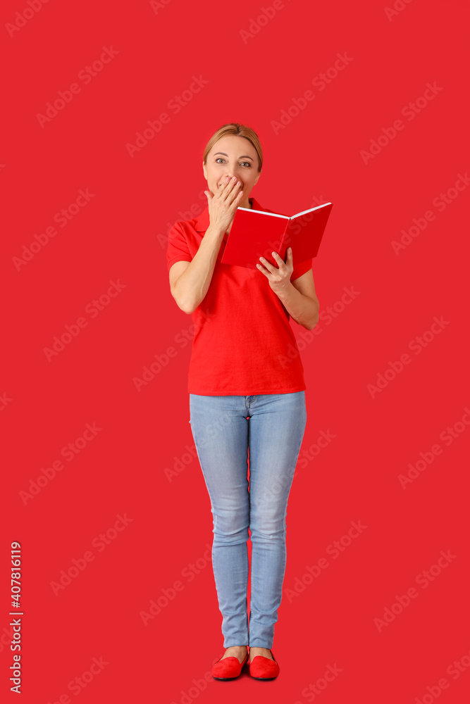 Surprised mature woman with book on color background