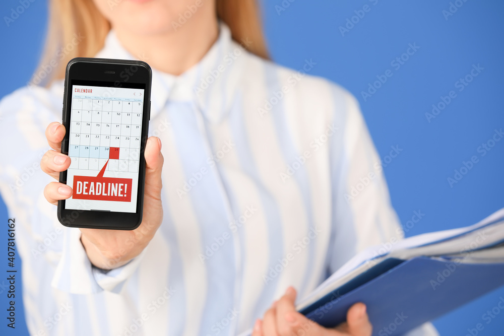 Woman with mobile phone and documents on color background. Concept of deadline