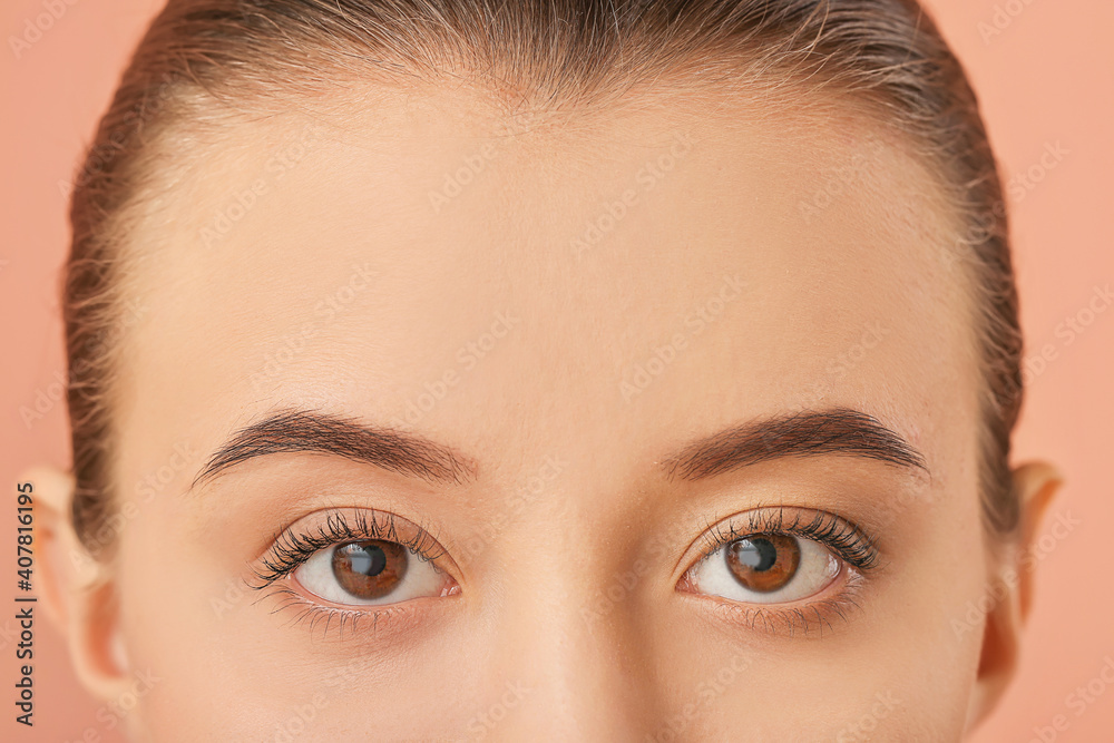 Young woman with beautiful eyebrows on color background, closeup