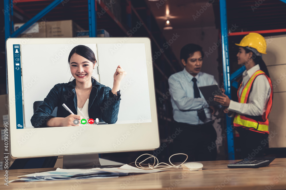 Warehouse staff talking on video call at computer screen in storage warehouse . Online software tech