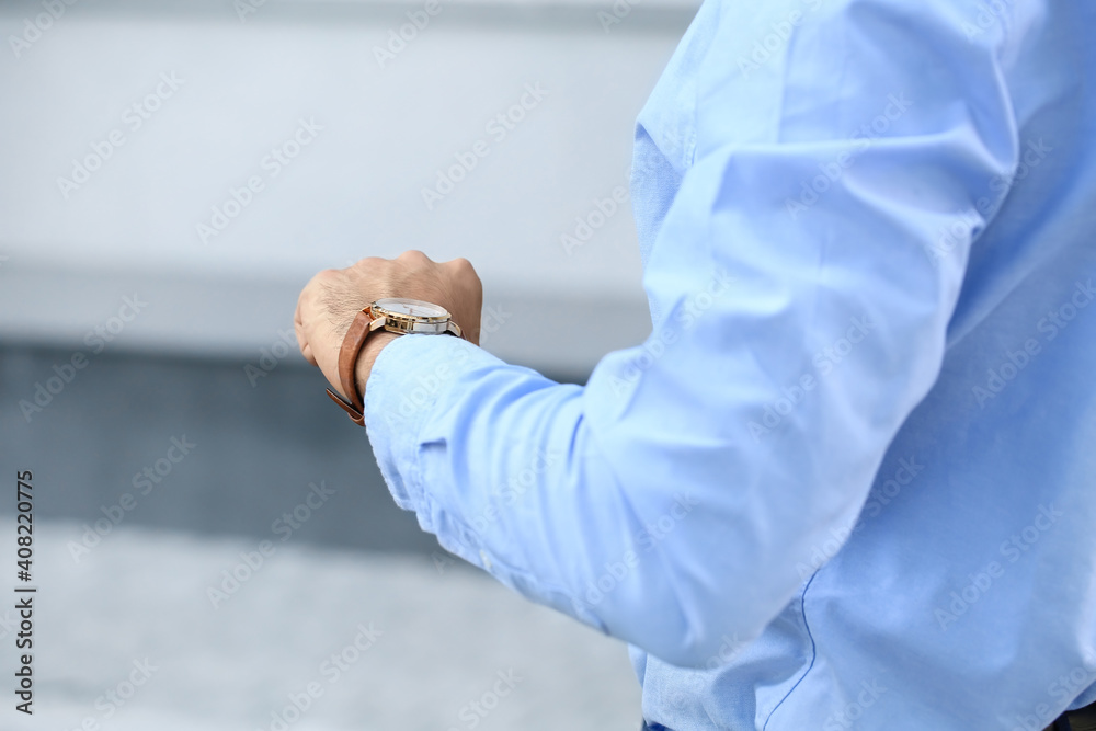 Young businessman looking at watch outdoors