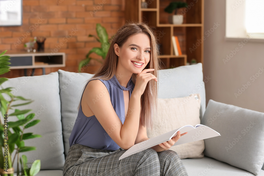 Beautiful woman with blank magazine in living room