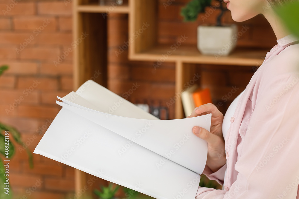 Young woman reading blank magazine in room