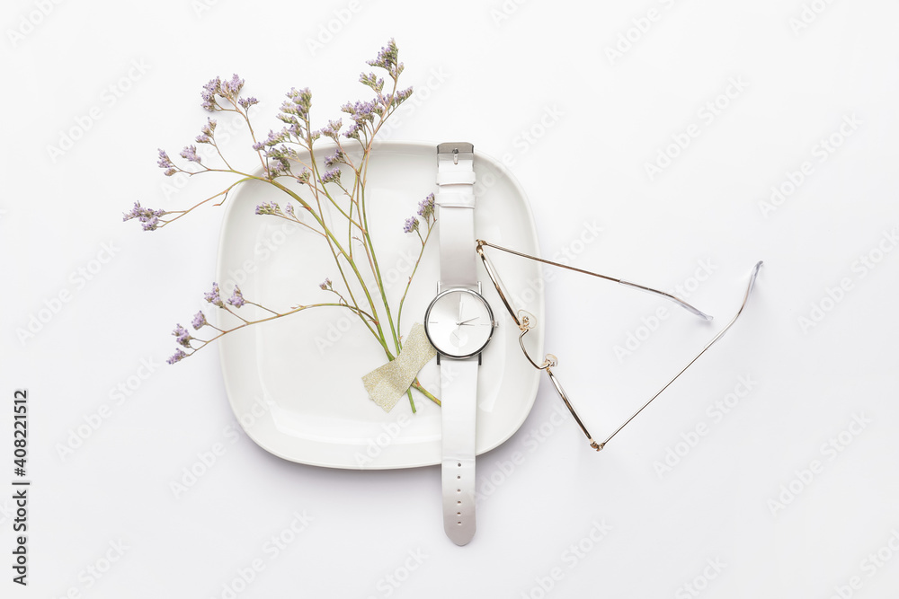 Stylish wristwatch, flowers and glasses on light background