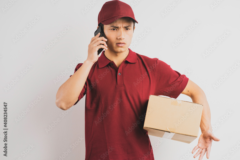 Portrait of a delivery man holding a cargo box and listening to the phone in the background