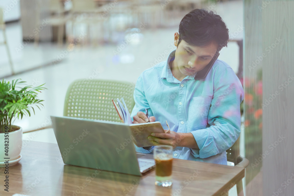 Asian man sitting working alone at a coffee shop