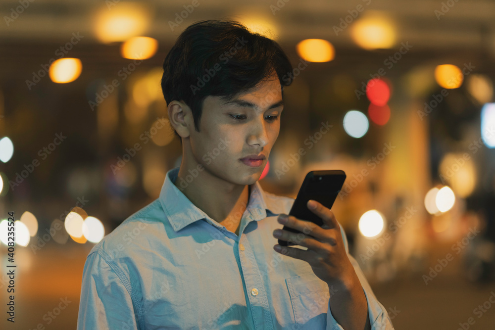 Man is standing using a cell phone in the sky in the evening