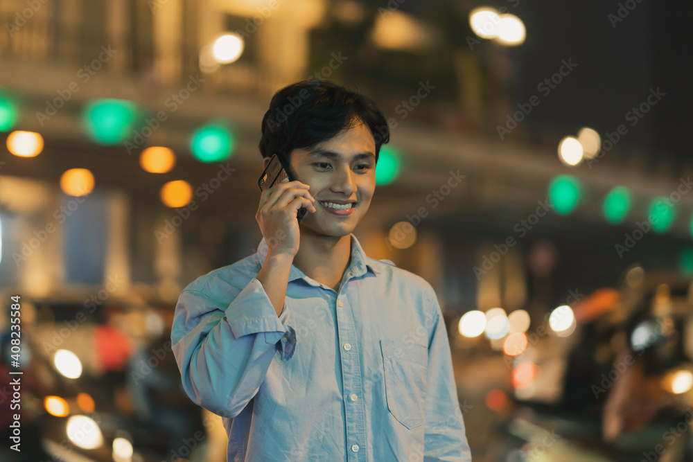 Man is standing using a cell phone in the sky in the evening