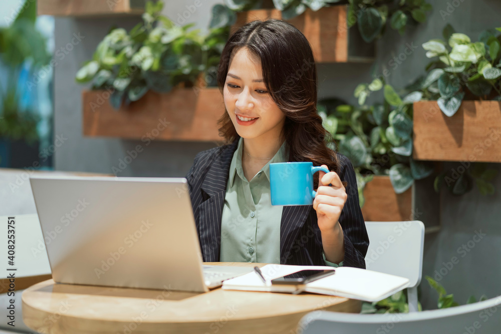 Cheerful young businesswoman working at the coffee shop