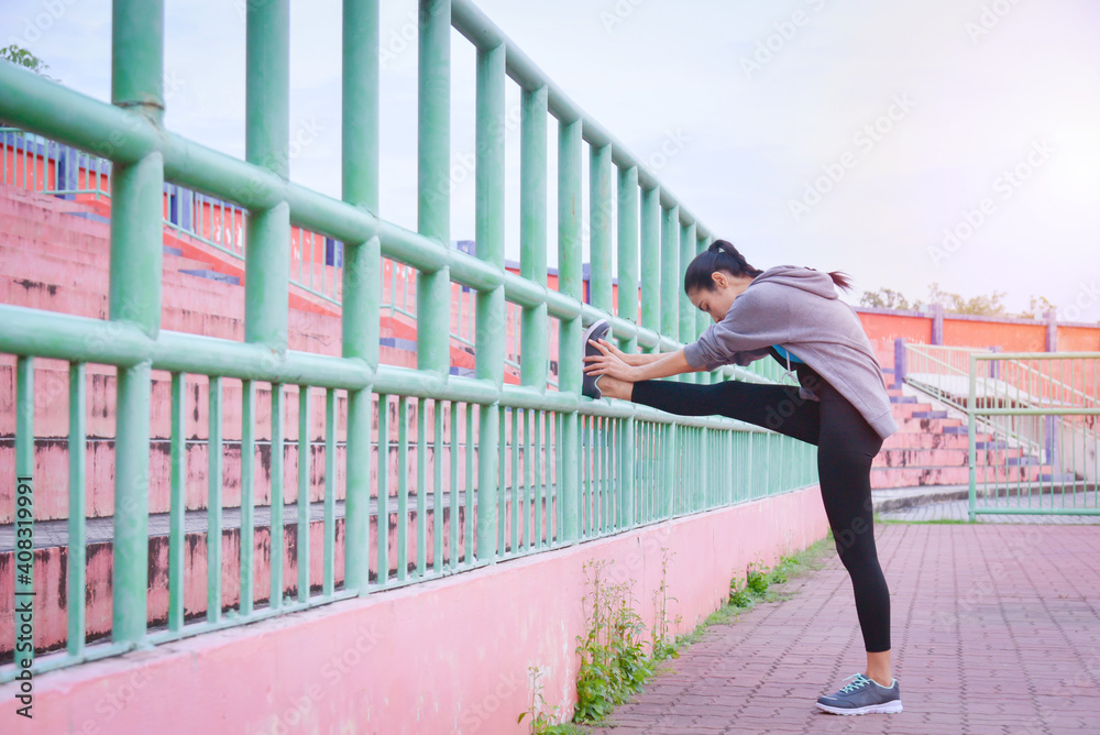 Beautiful asian woman in sportswear stretching before run outdoors in the city.