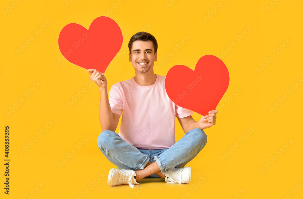 Handsome man with big red hearts on color background