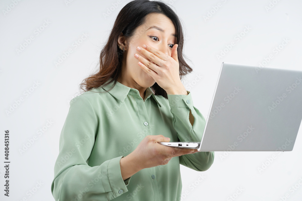 Portrait of the beautiful Asian businesswoman looking at the laptop screen with a surprised look