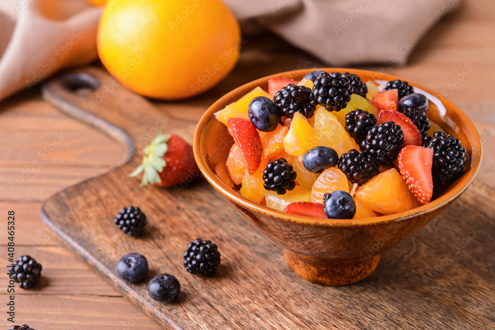 Bowl with fruit salad on wooden background