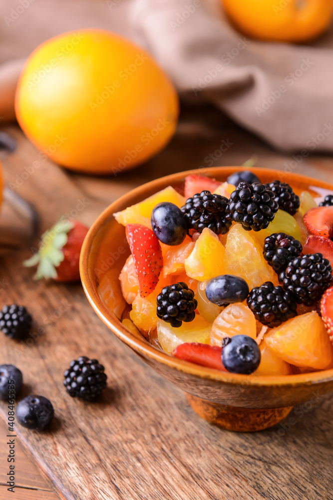 Bowl with fruit salad on wooden background