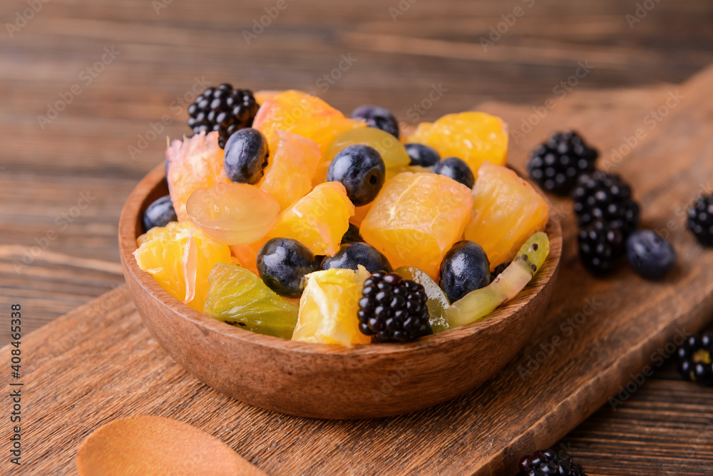 Bowl with fruit salad on wooden background