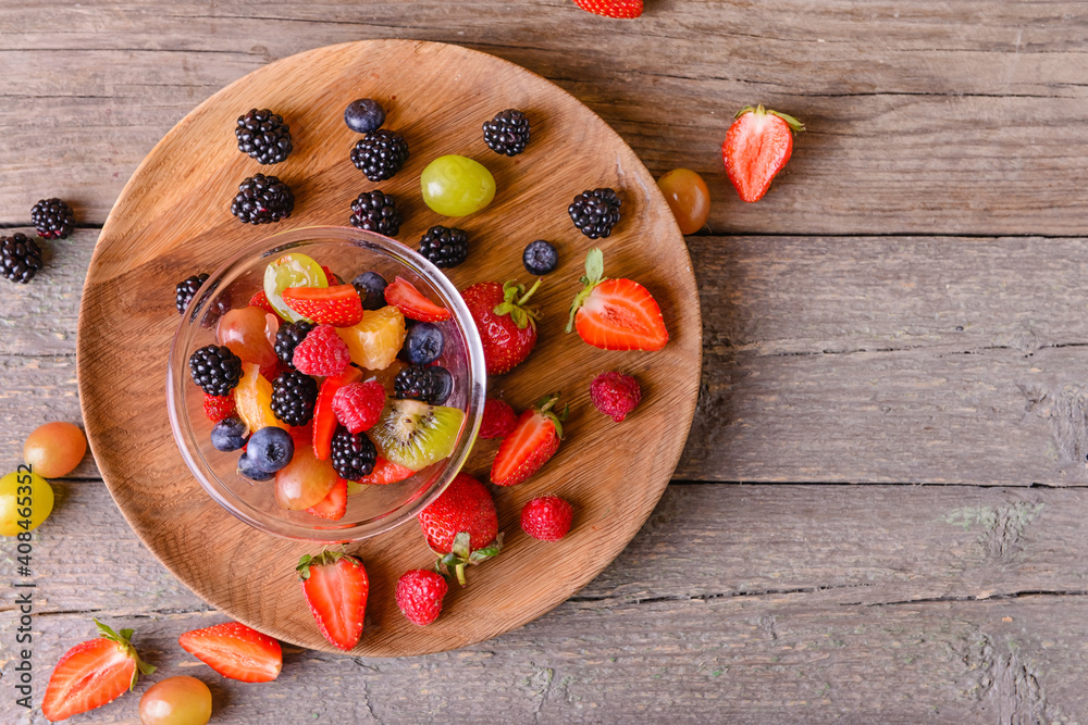 Bowl with fruit salad on wooden background