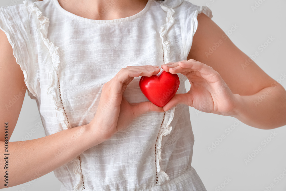 Young woman with red heart on grey background, closeup