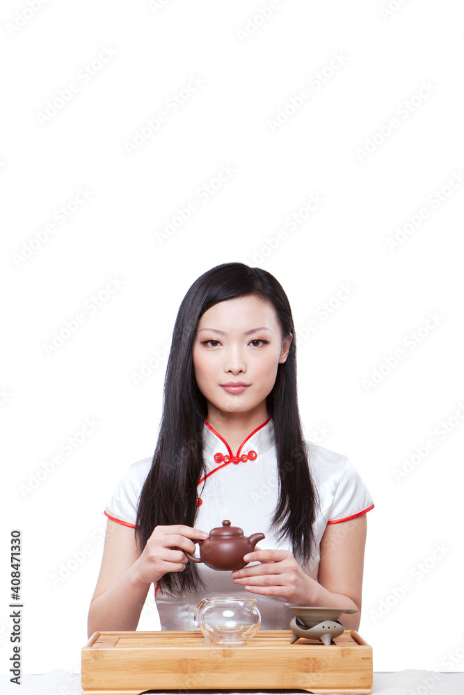 Wearing cheongsam Oriental young woman in preparation for the tea ceremony