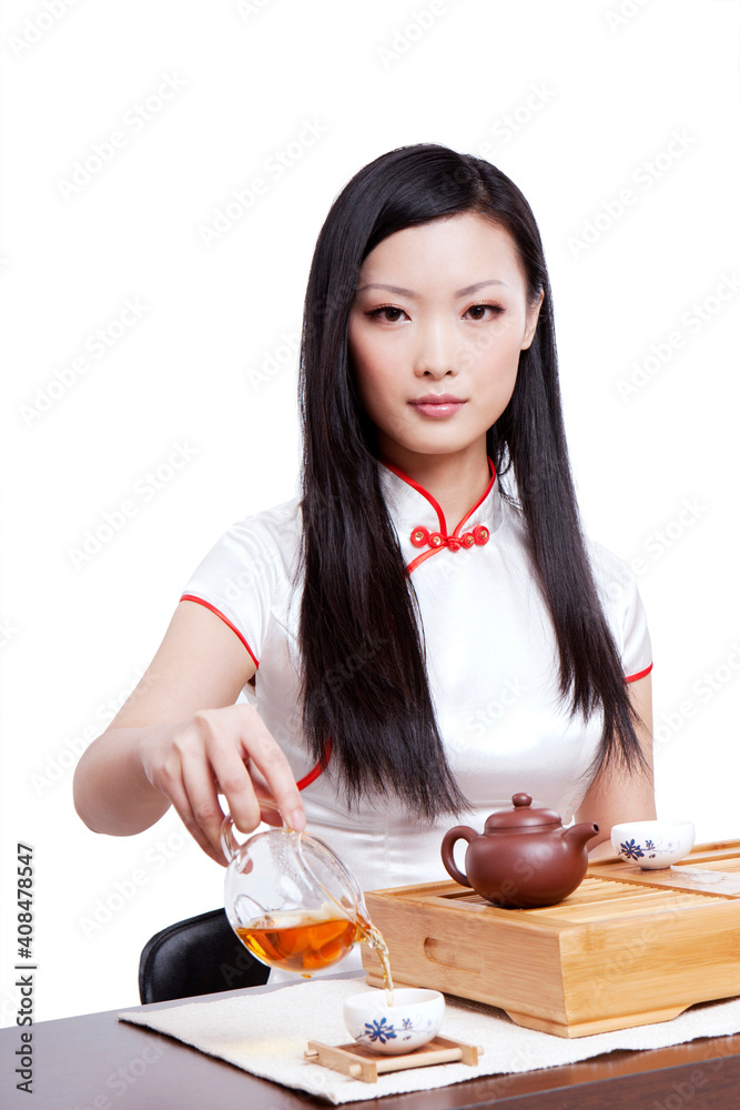 Wearing cheongsam Oriental young woman in preparation for the tea ceremony