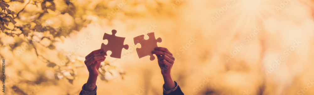 Silhouette of the human hand with piece of jigsaw outdoors on the nature background.