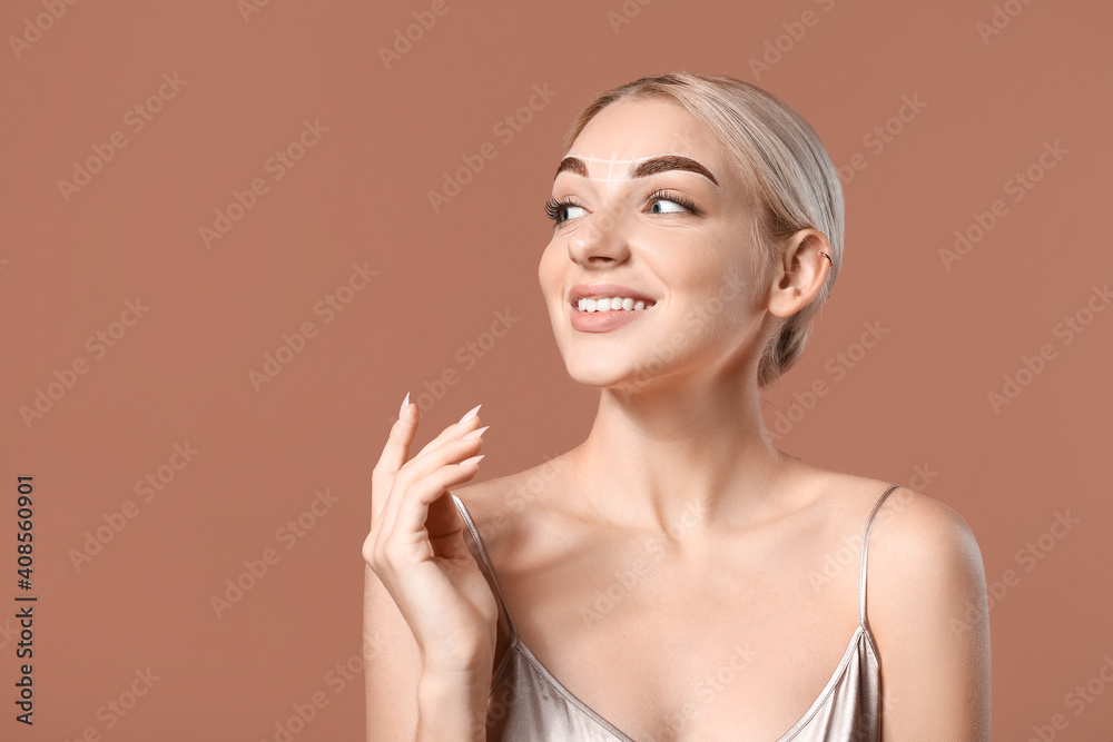 Young woman with marking for eyebrow correction on color background