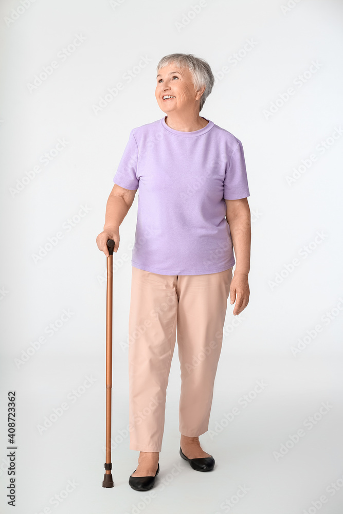 Senior woman with walking stick on white background