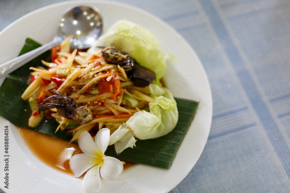 The Spicy papaya salad called `Somtum` in Thai on wooden table