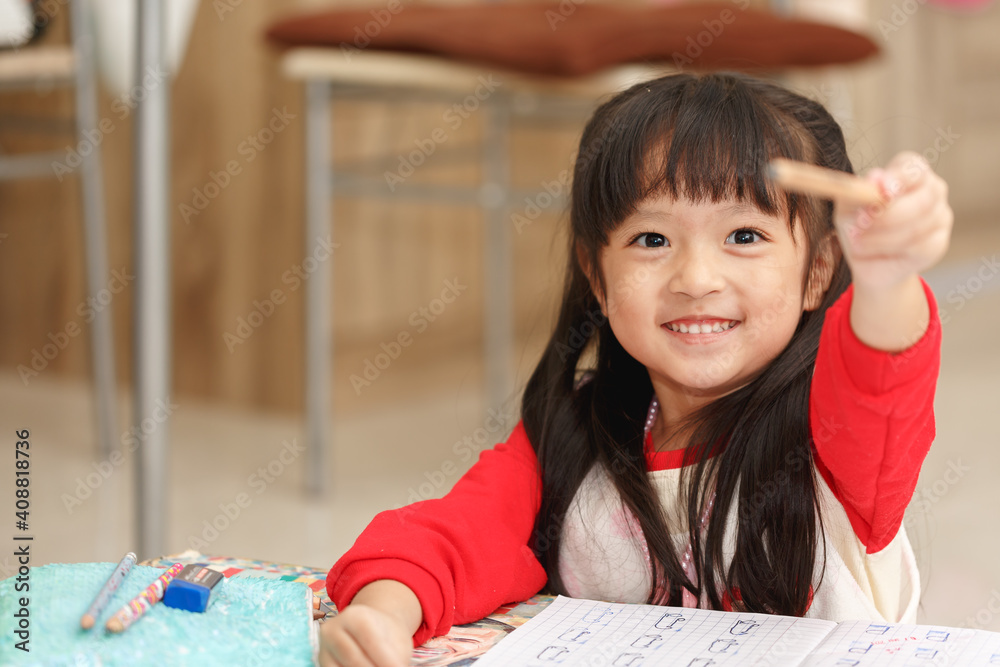 亚洲小女孩用铅笔在笔记本上学习和写作