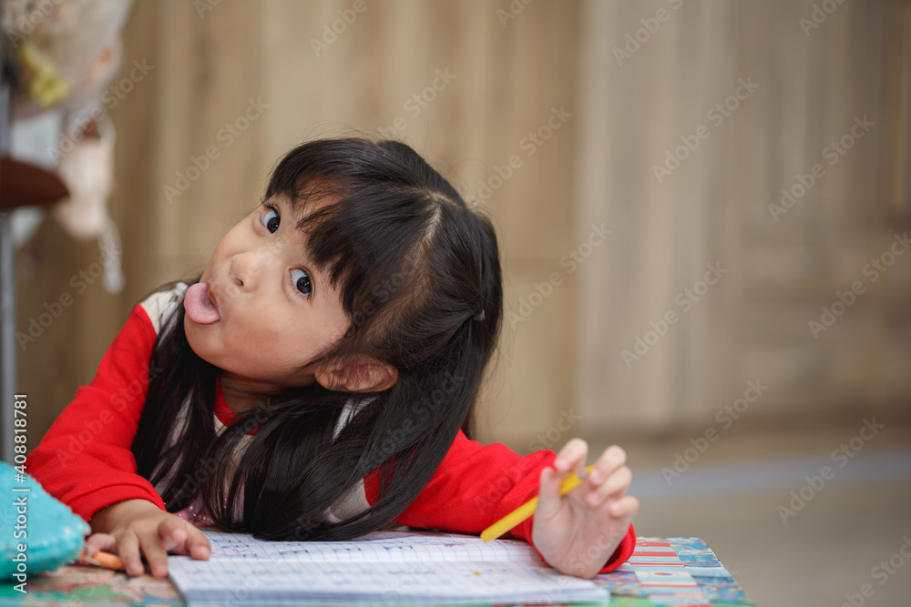 Asian little girl learning and writing in notebook with pencil