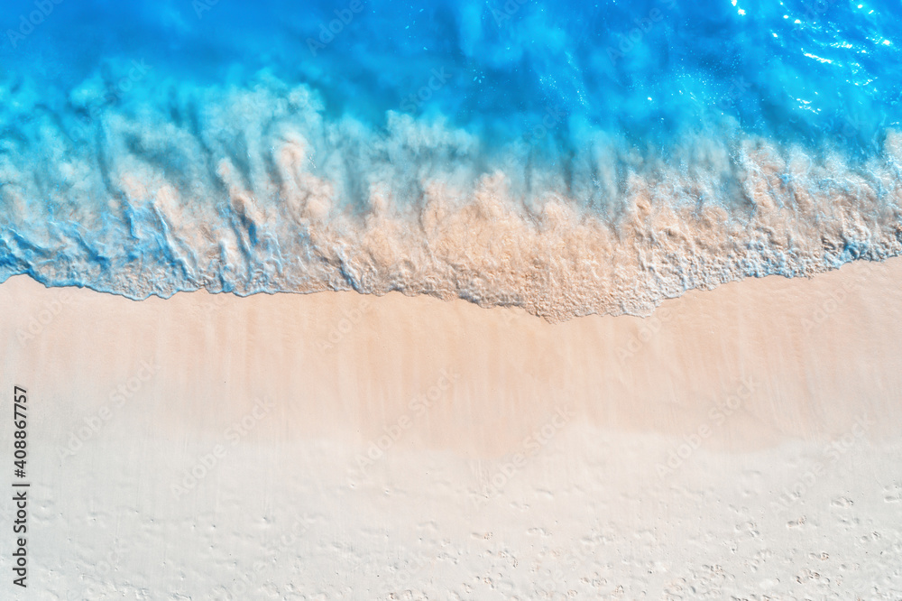 Aerial view of clear blue sea with waves and empty white sandy beach at sunset. Summer in Zanzibar, 